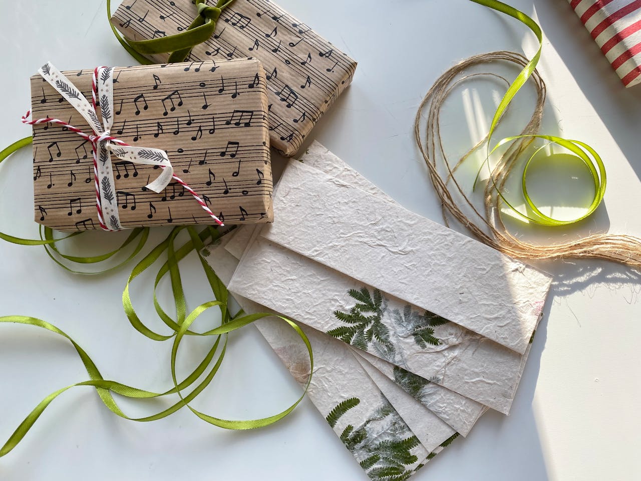 Beautifully wrapped gifts with music note paper and green ribbons in the warm sunlight.