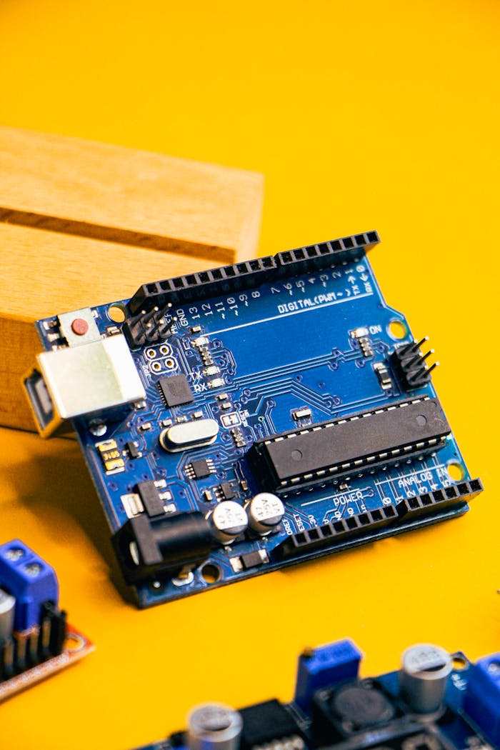 Close-up of an Arduino microcontroller on a vibrant yellow background, showcasing electronic innovation.
